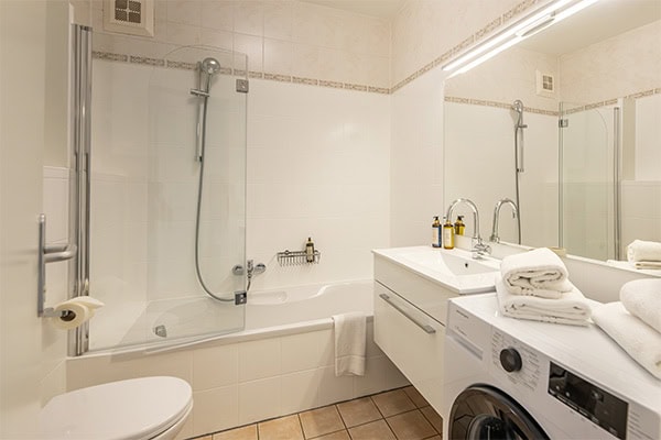 Modernes Badezimmer Helles Badezimmer mit Badewanne, Waschbecken und Waschmaschine.