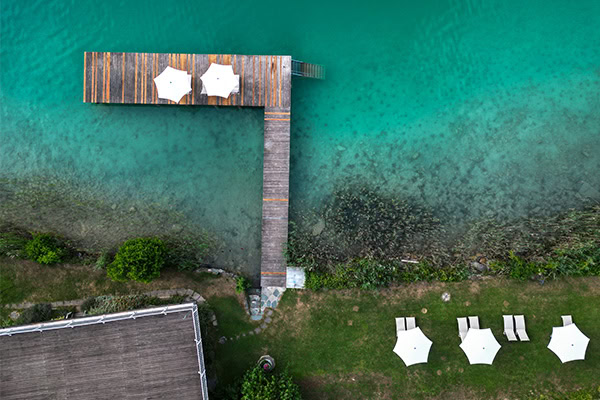 Blick von oben auf den See Aerial view of a wooden pier with two sunbeds and umbrellas am See.